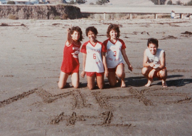 During the beach trip in 1985 when coach Jim White took the teams to Cayucos following the Santa Maria Invitational, Herlinda Gonzalez wrote "MHS #1" in the sand. From left is Herlinda, Delfina Herrera, Sylvia Diaz and her brother, Raul Diaz. The photo was taken with Raul's camera by a teammate and are the only known images of the real beach trip depicted in the movie "McFarland USA.".